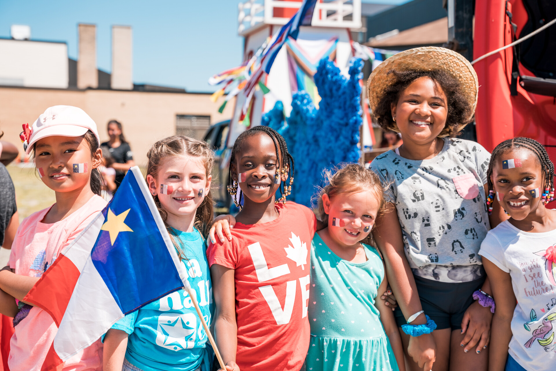 A picture of young girls from various backgrounds together in front of a parade float